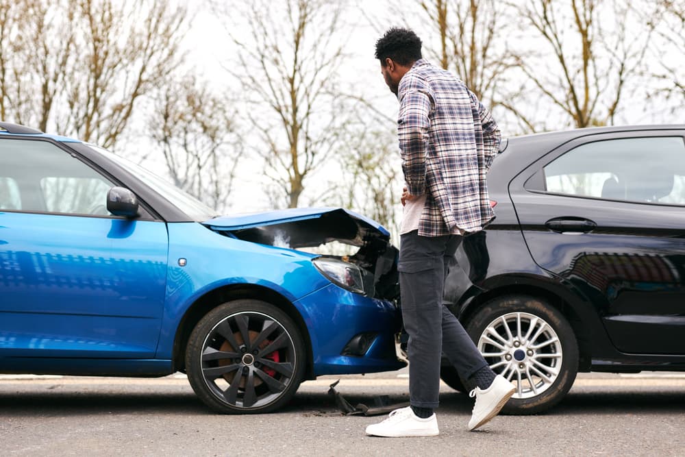 A Young man looking at damaged car hit from behind after the accident in Bronx.