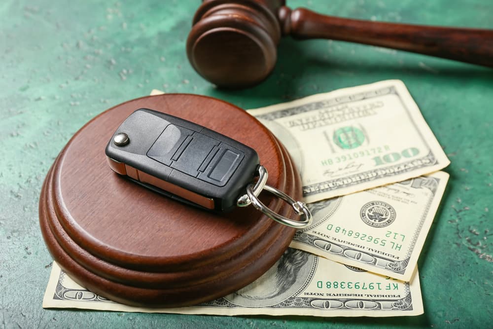 Wooden gavel along with car key and dollar amount