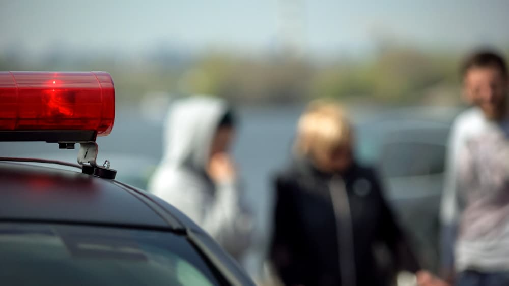 Car accident, witnesses standing near crashed automobiles police lights flashing