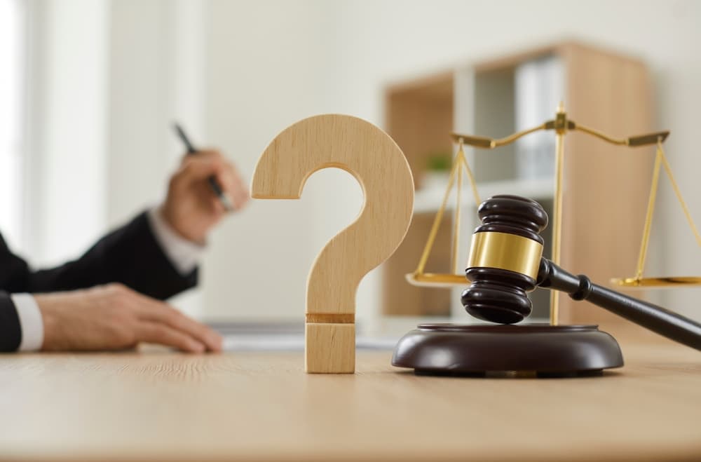 Wooden question mark and gavel on the judge's table in the courtroom or on the desk in the lawyer's office.