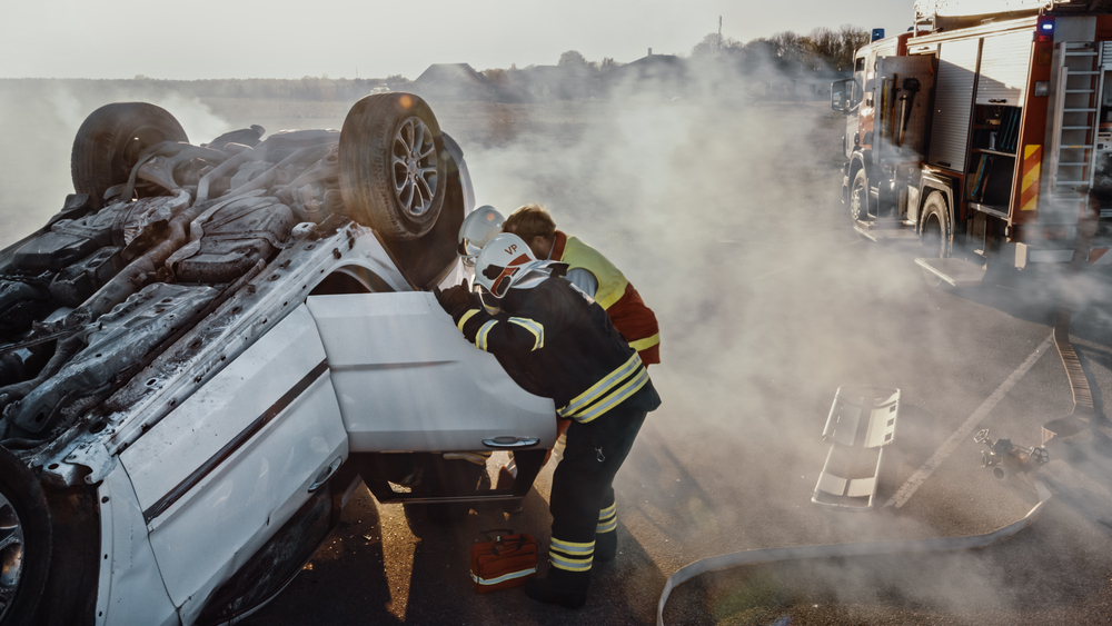 Firefighters assisting at the scene of an overturned car after a serious accident.