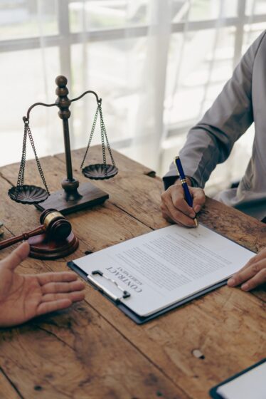 A lawyer explains to a client the law that must be applied to a court case. With contract documents and wooden gavel on the table in the courtroom Justice and law. Vertical image